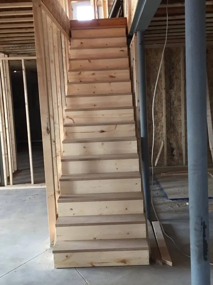 Framed stairway with stringers and treads between stud walls